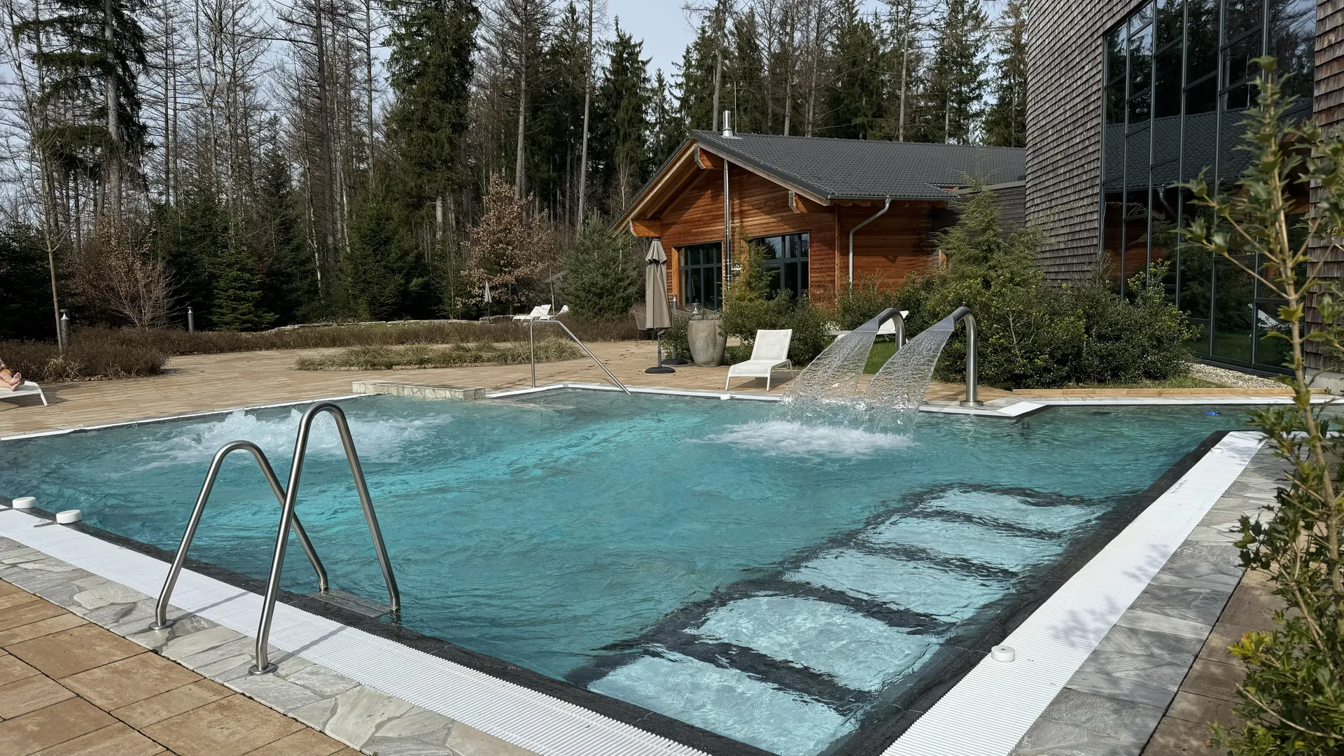 Sprudelbecken mit Wasserdüsen im Außenbereich des Deep Nature Spa Park Allgäu mit Holzhütte im Hintergrund