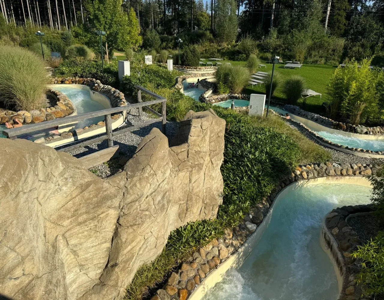 Außenbereich des Aqua Mundo im Center Parcs Park Allgäu mit Erlebniskanälen zwischen Felsen und Wiese