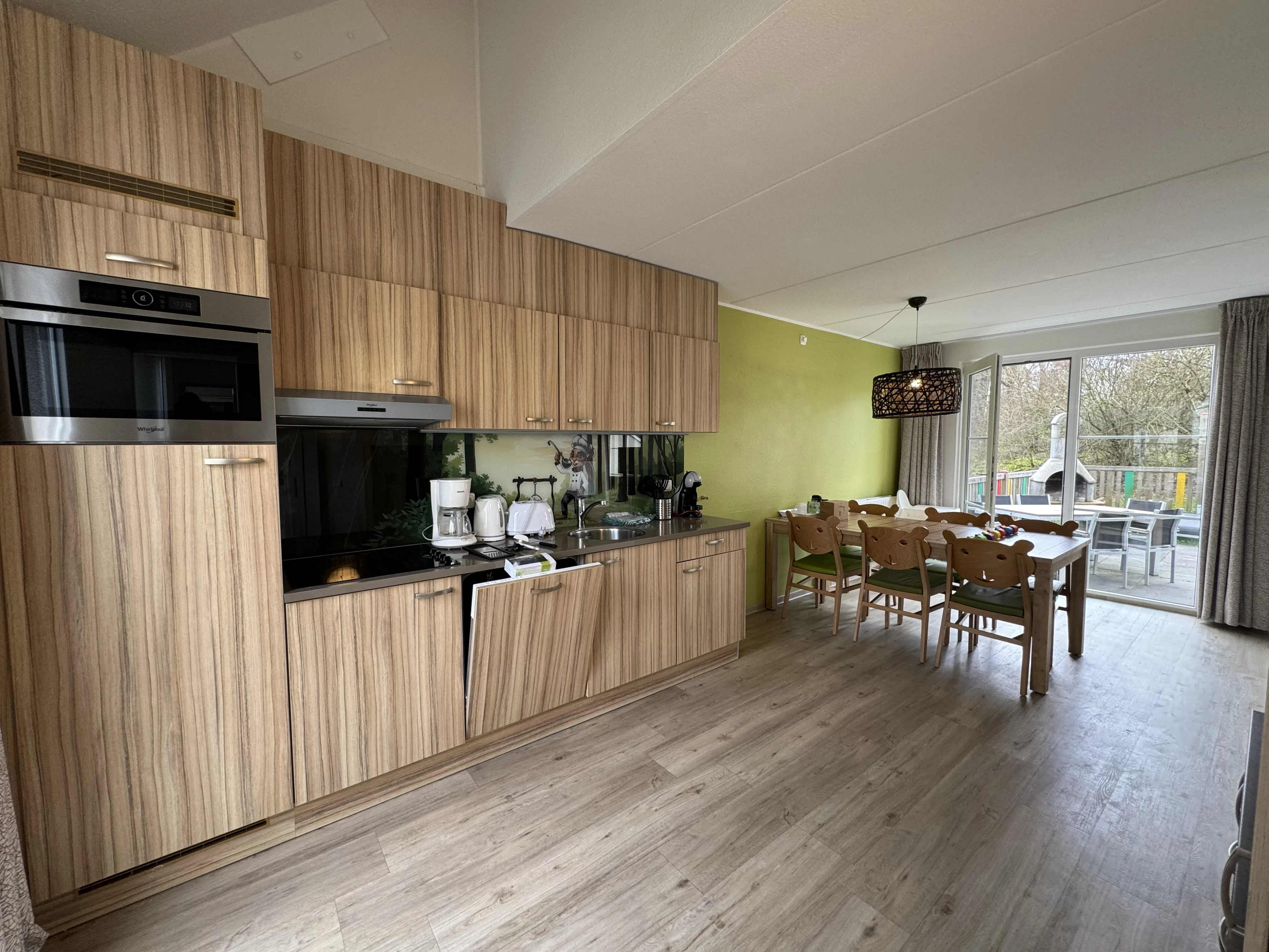 Die offene Küche mit Esstisch und süßen Kinderstühlen – im Hintergrund die Terrasse mit Spielplatz