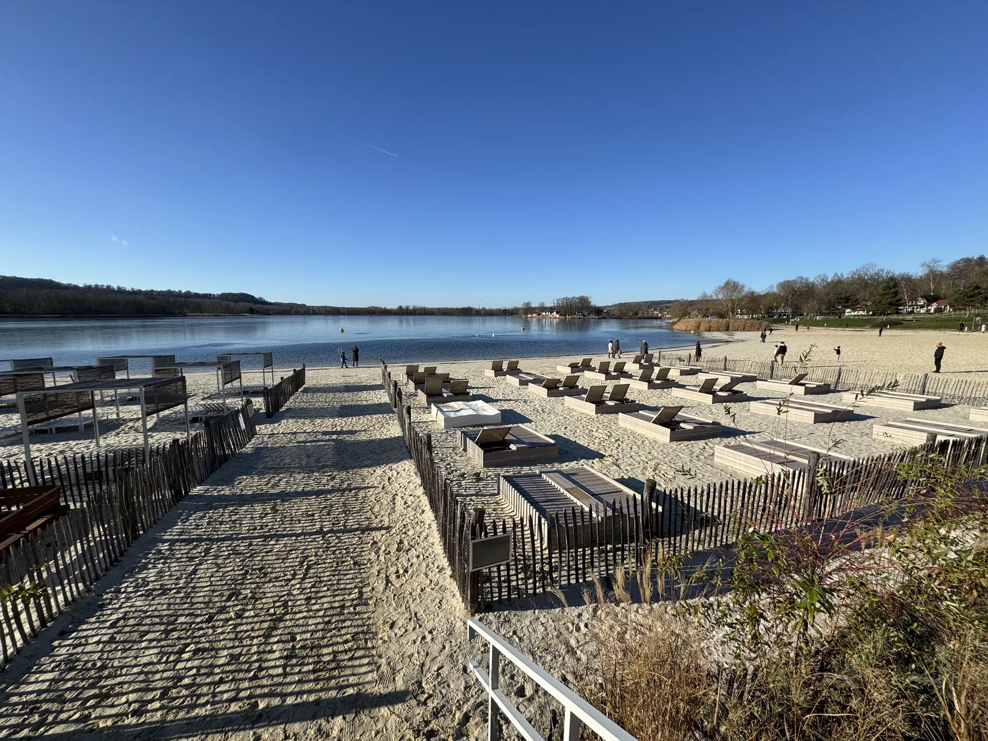 Blick über das Strandbad am Lac de l’Ailette mit Außengastronomie und Seeufer