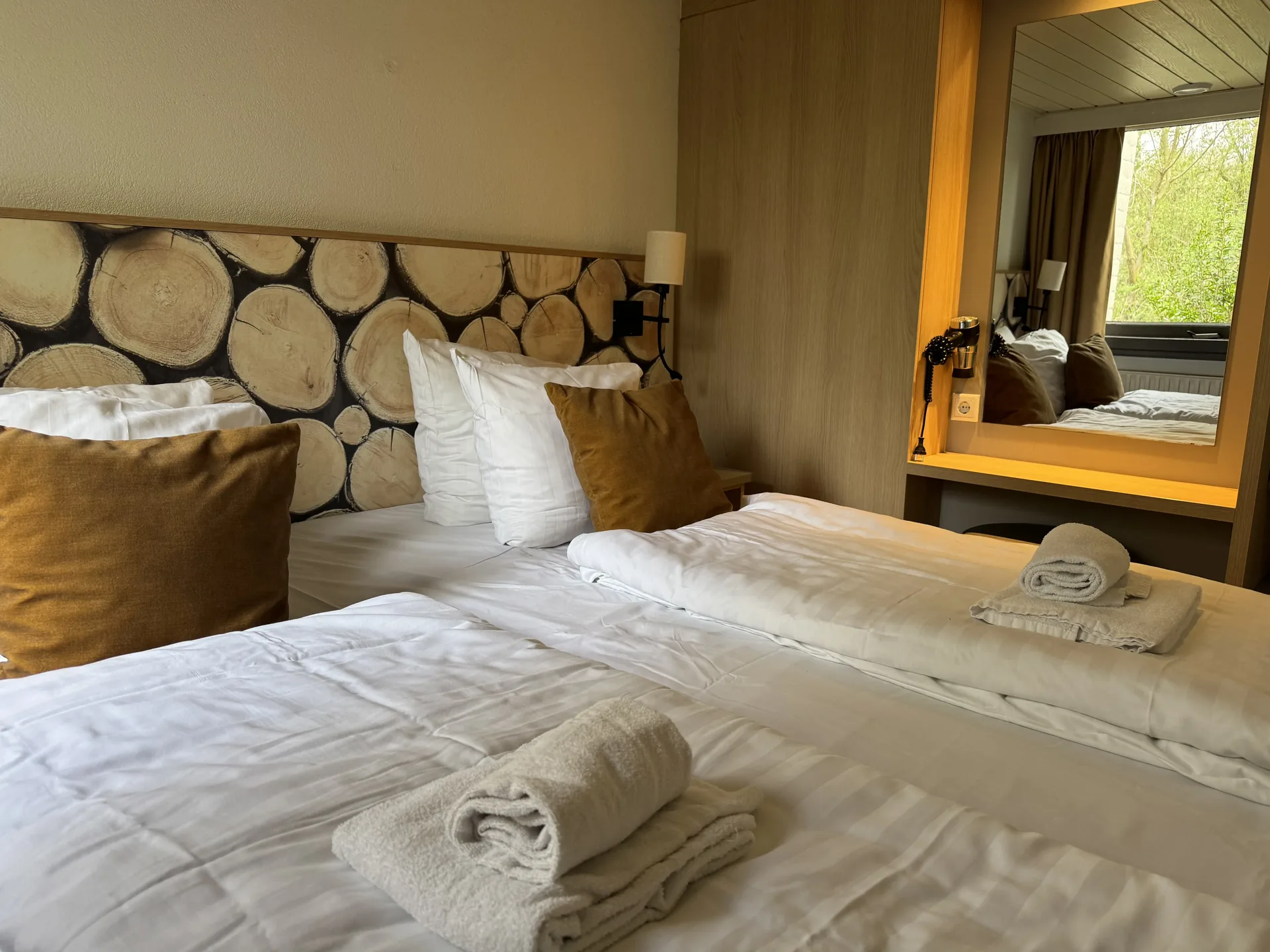 Doppelbett mit Holzscheiben-Kopfteil und Wandleuchten im VIP-Ferienhaus für 4 Personen