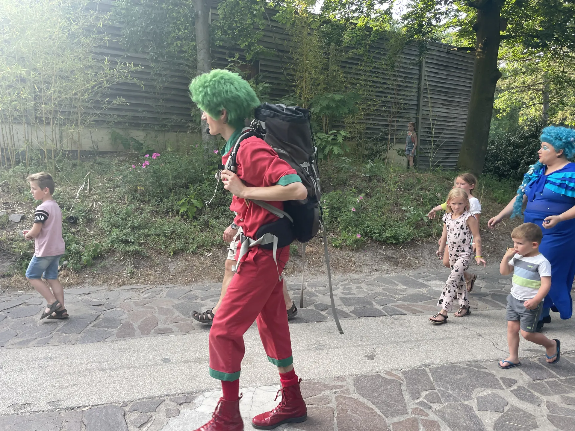 Maskottchen Orry mit grünen Haaren und rotem Anzug spaziert mit Kindern durch den Center Parcs Het Heijderbos