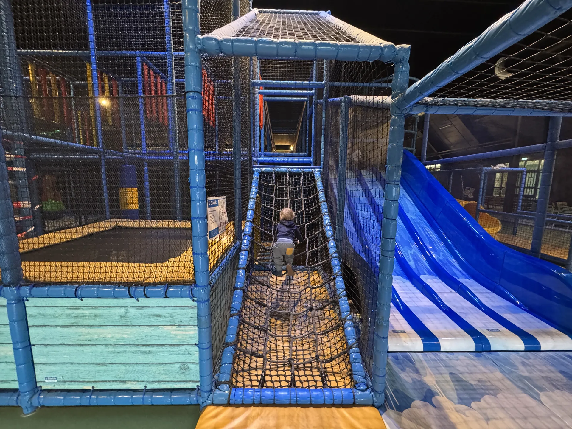 Netzbrücke und blaue Rutschen im Klettergerüst