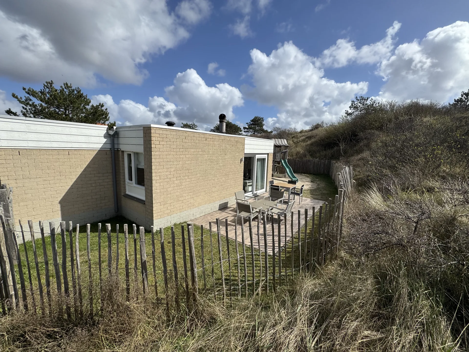 Beach Chilla von außen, eingebettet in die Dünenlandschaft mit Holzzaun