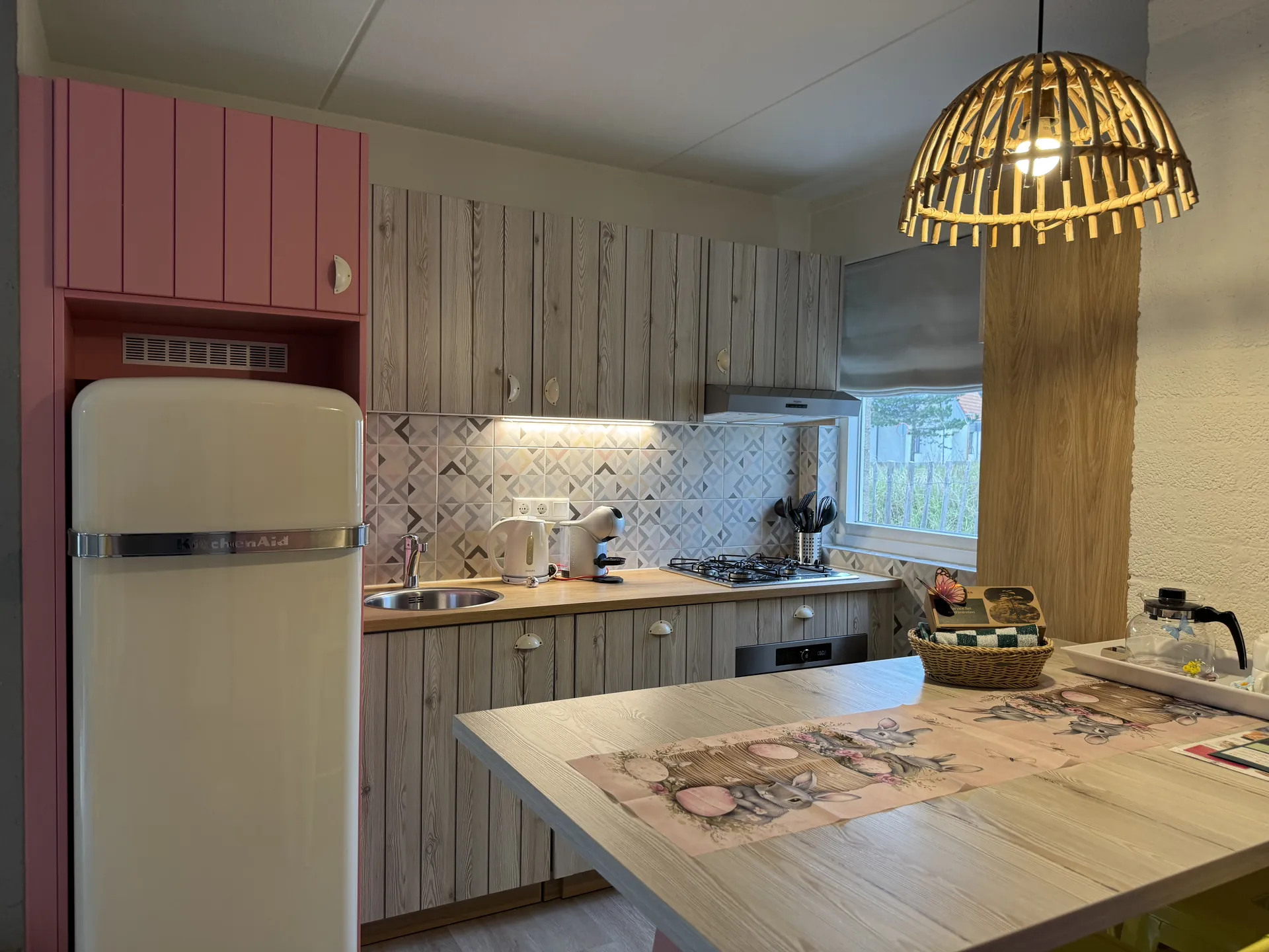 Küche mit Retro-Kühlschrank, Holzfronten und Korblampe über dem Esstisch