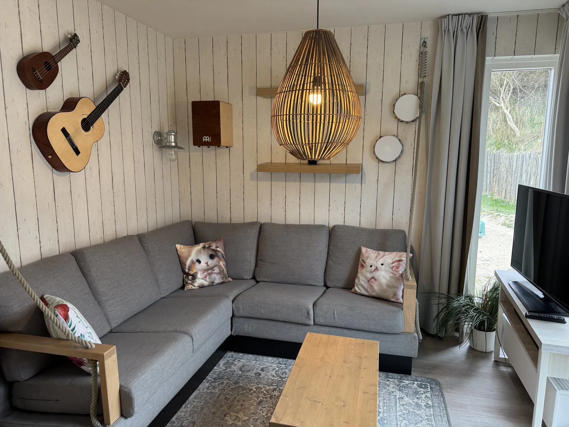 Wohnzimmer mit Eckcouch, Gitarre und Ukulele an der Wand