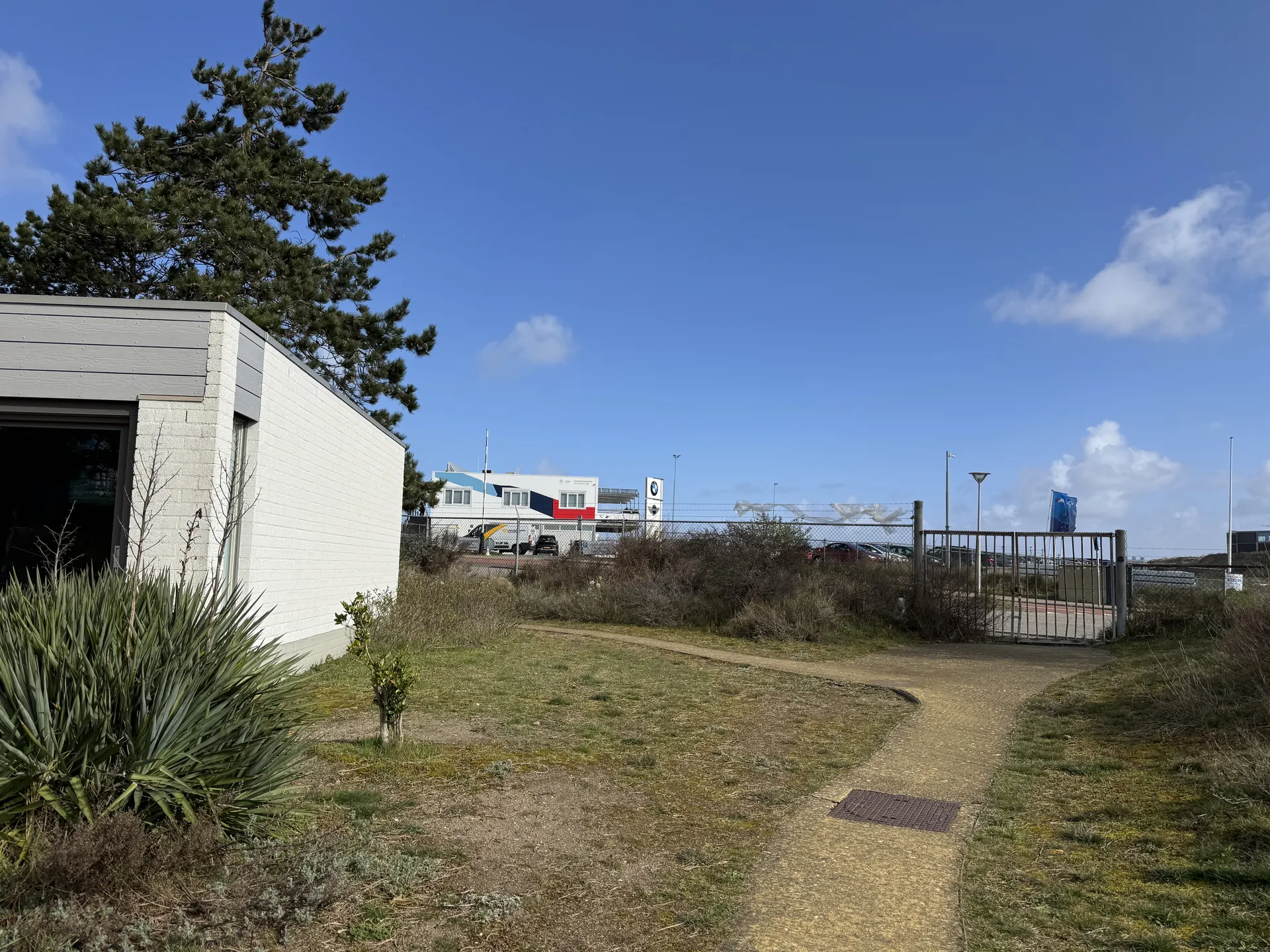 Außenansicht des Comfort-Ferienhauses mit Blick auf den Parkweg und die umliegende Dünenlandschaft