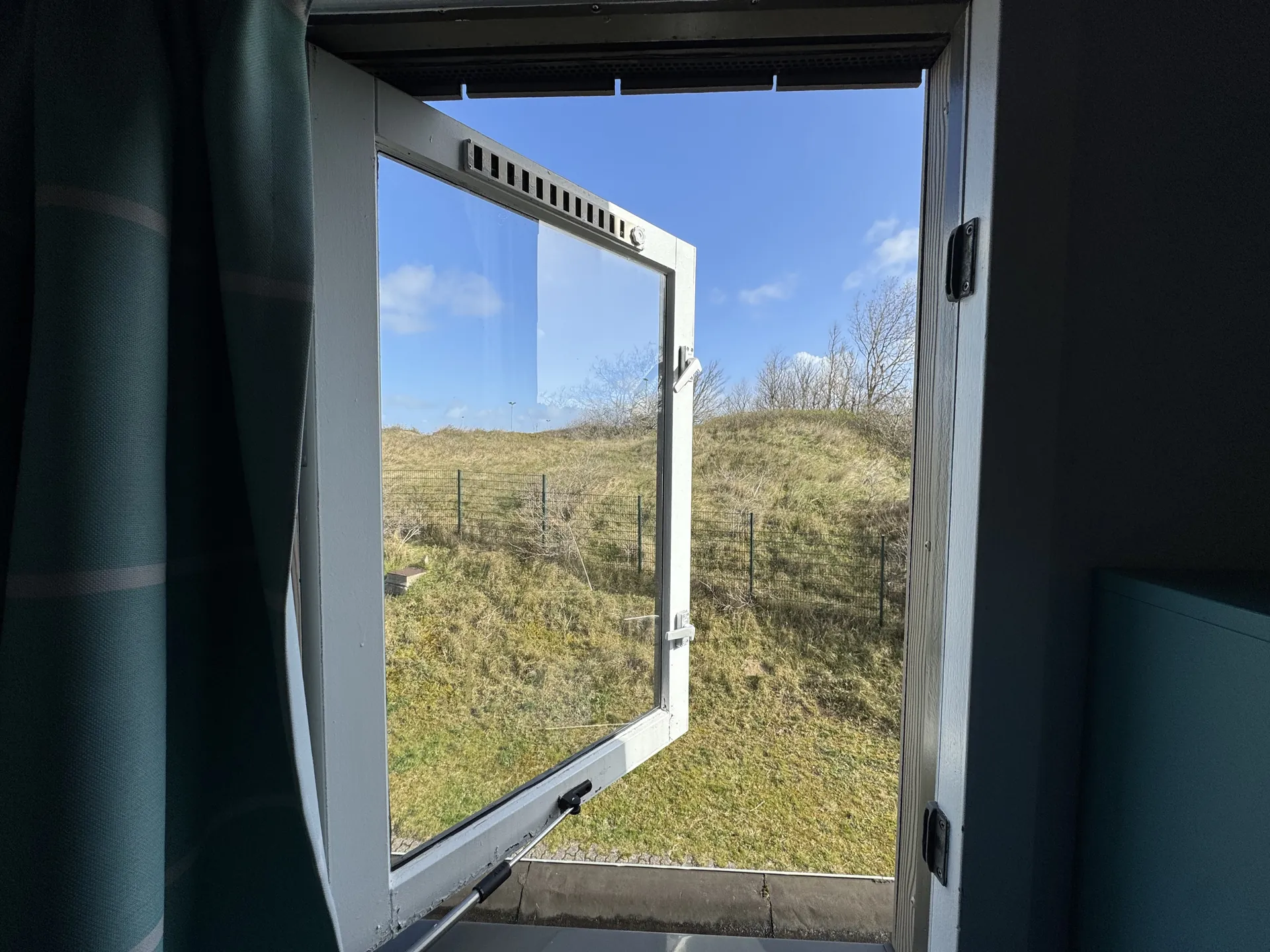 Blick durch das geöffnete Fenster auf die Dünenlandschaft