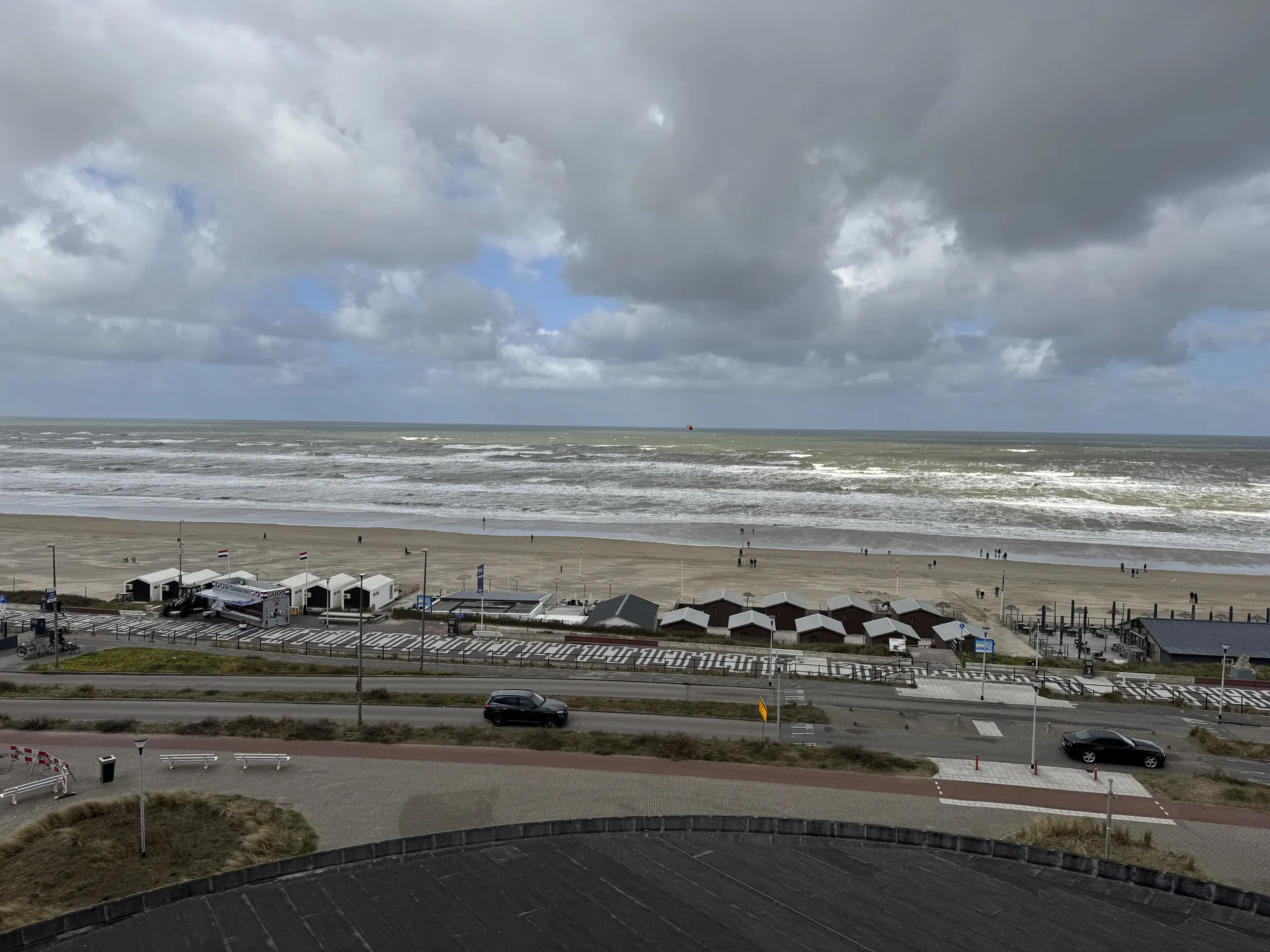 Panoramablick vom Hotelzimmer auf den breiten Nordseestrand mit Strandhütten und Wellen
