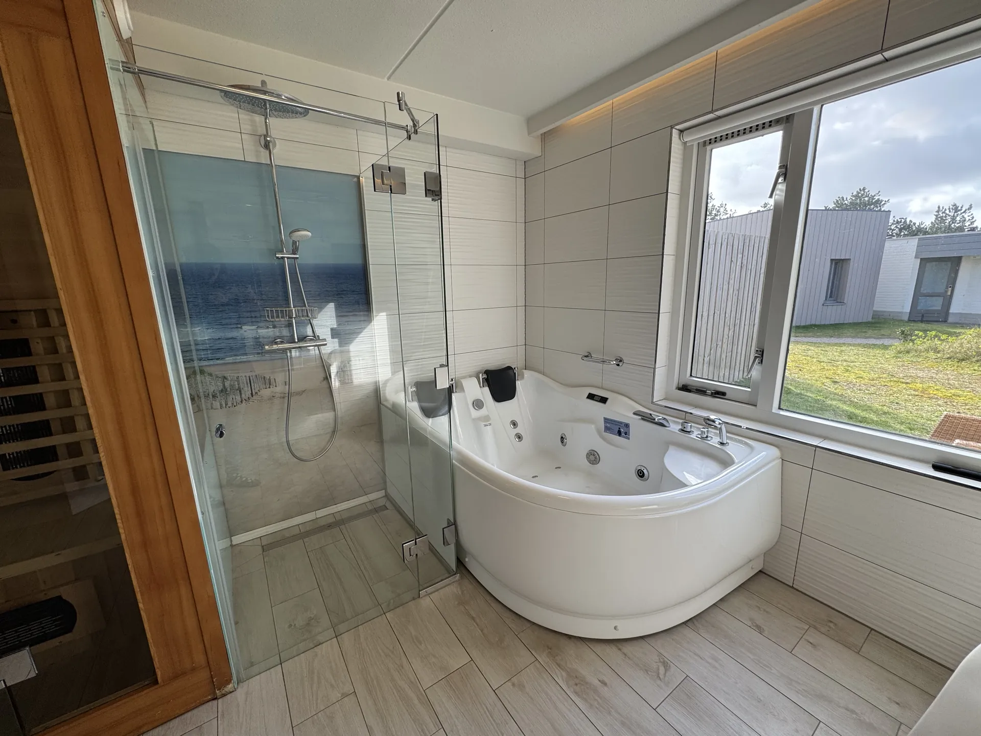 Großes Badezimmer mit Eckwhirlpool, Glasdusche und Blick auf die Infrarot-Sauna