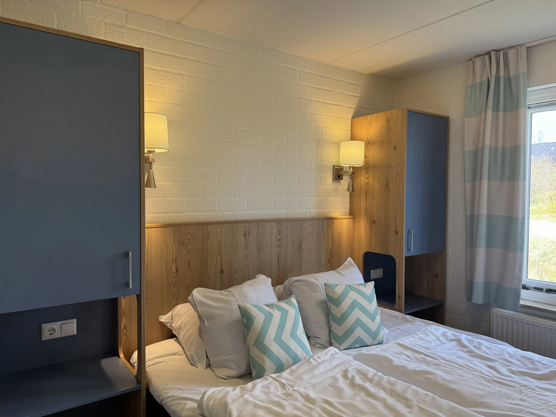Blick ins Schlafzimmer mit blauem Kleiderschrank und Wanddetails