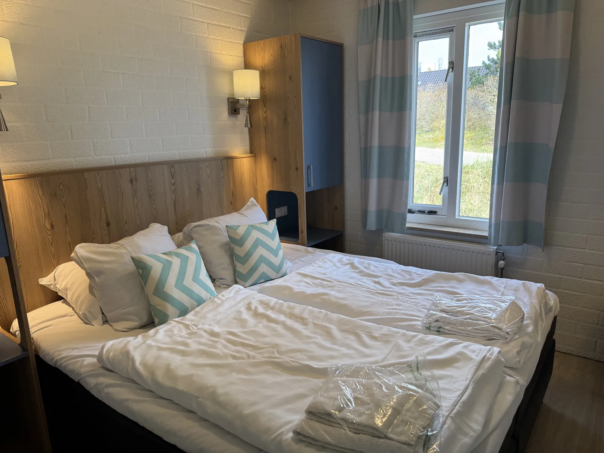 Doppelbett im VIP-Schlafzimmer mit Zickzack-Dekokissen und Wandleuchten