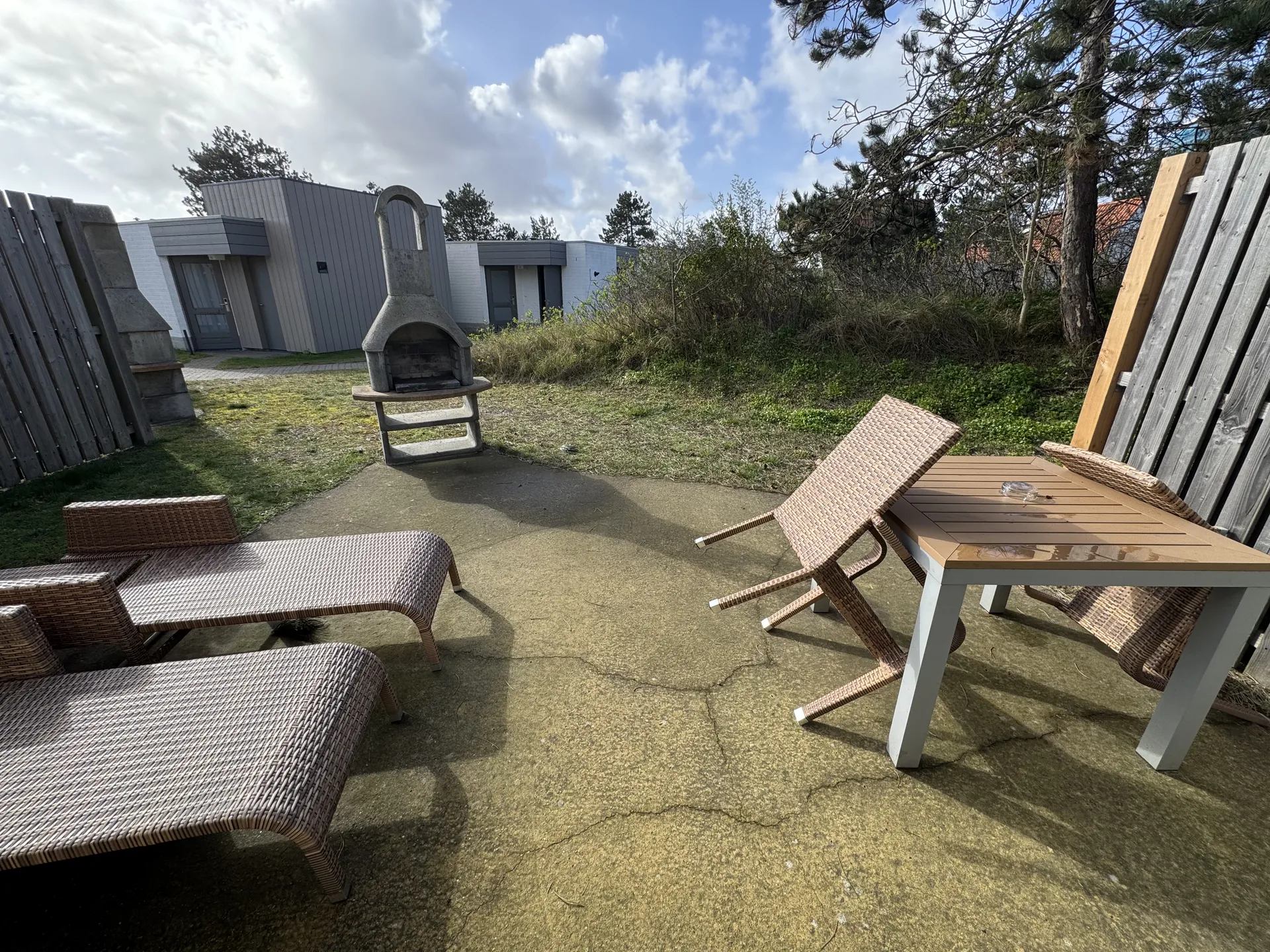 Terrasse mit Rattanmöbeln, Sonnenliegen und gemauertem Grill
