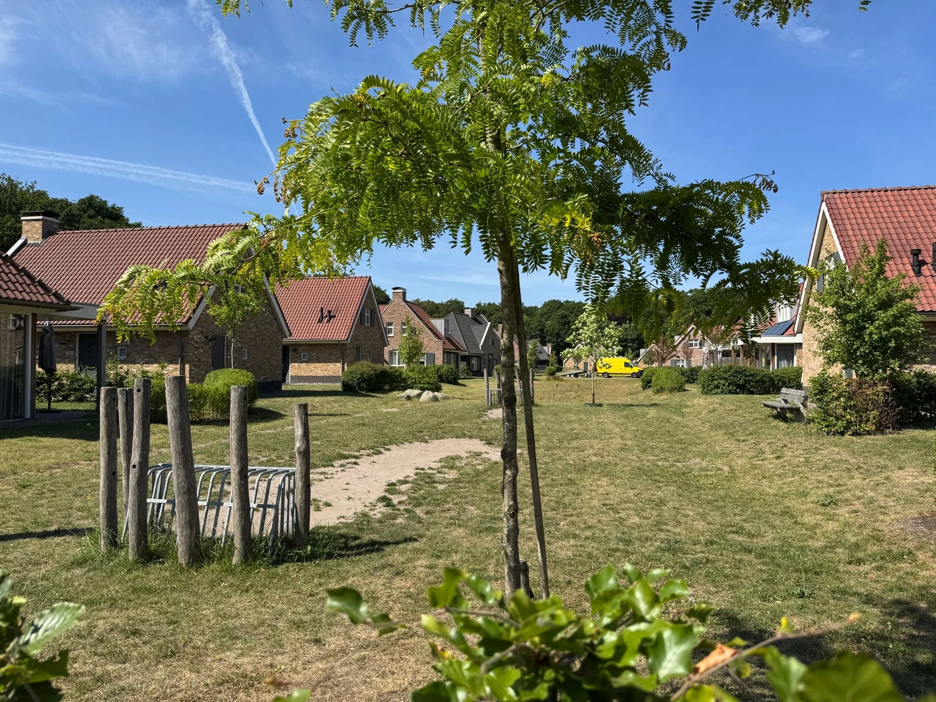 Klassische Backsteinhäuser mit roten Ziegeldächern im älteren Teil des EuroParcs Kaatsheuvel, dazwischen Rasenflächen und Fahrradständer