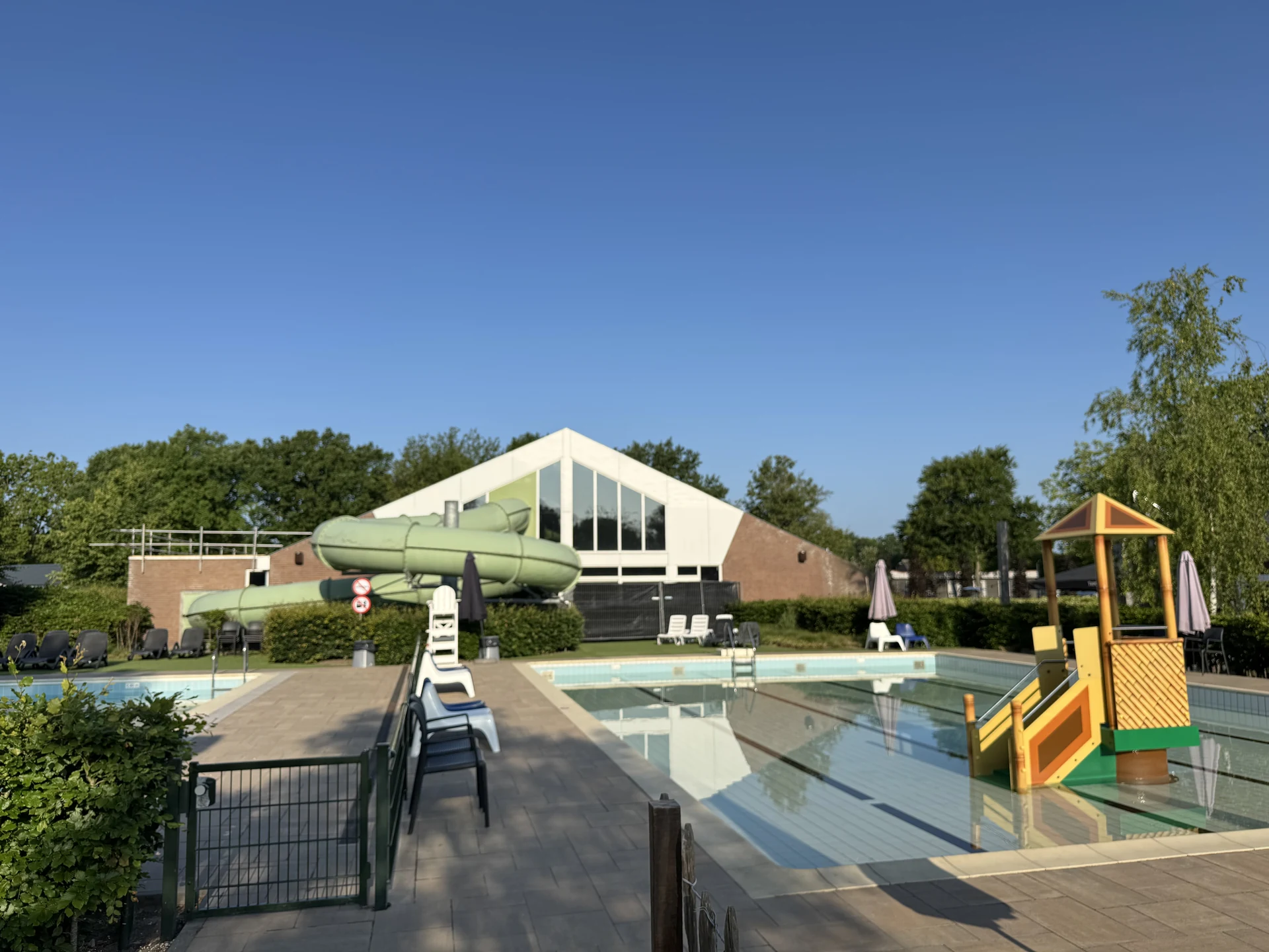 Kinderbecken mit Wasserspielturm im EuroParcs Kaatsheuvel, dahinter die grüne Röhrenrutsche und die Halle des Hallenbads