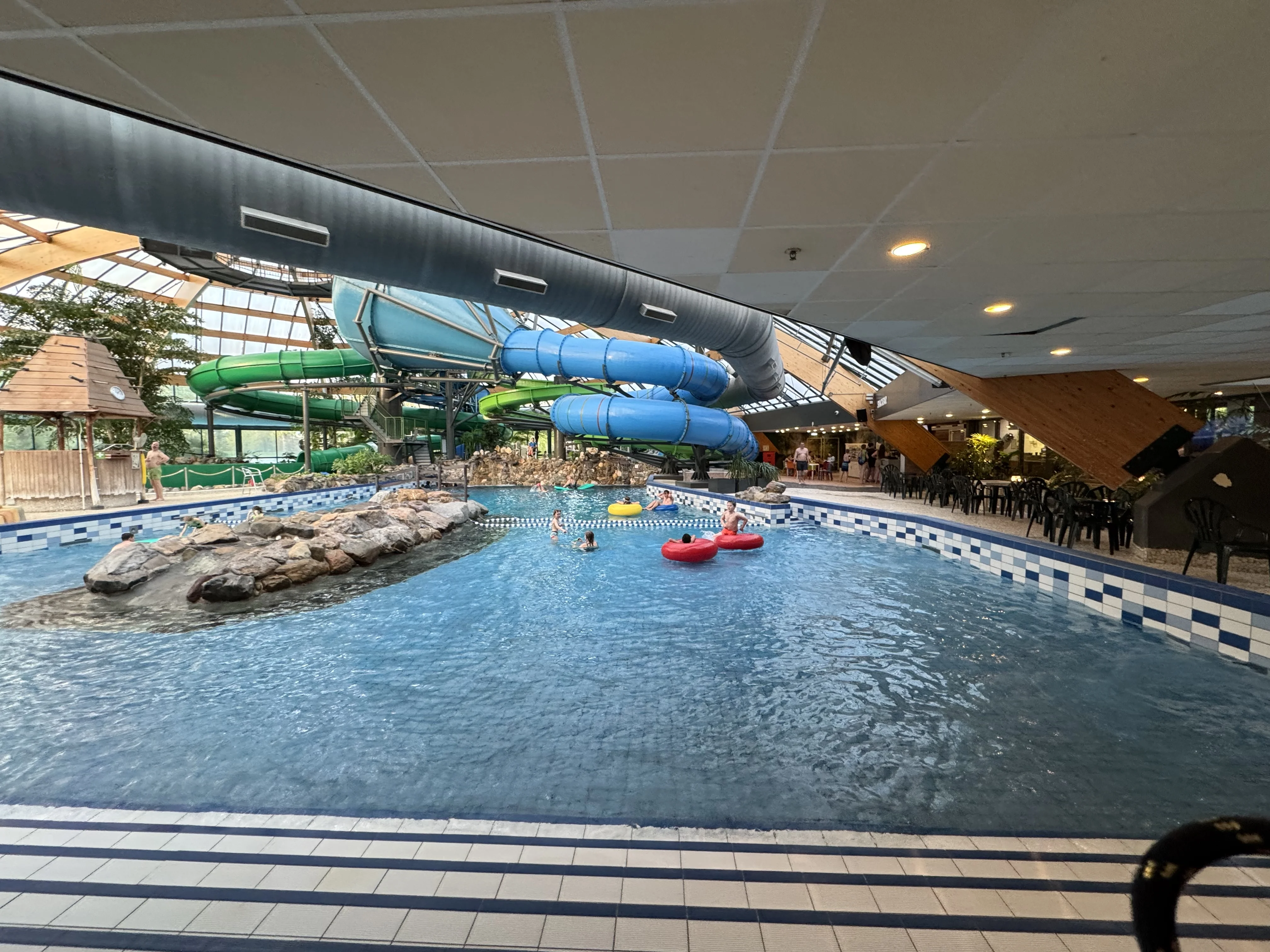 Das Schwimmbad bei Tag – Familien im Wellenbecken mit Blick auf die Rutschen