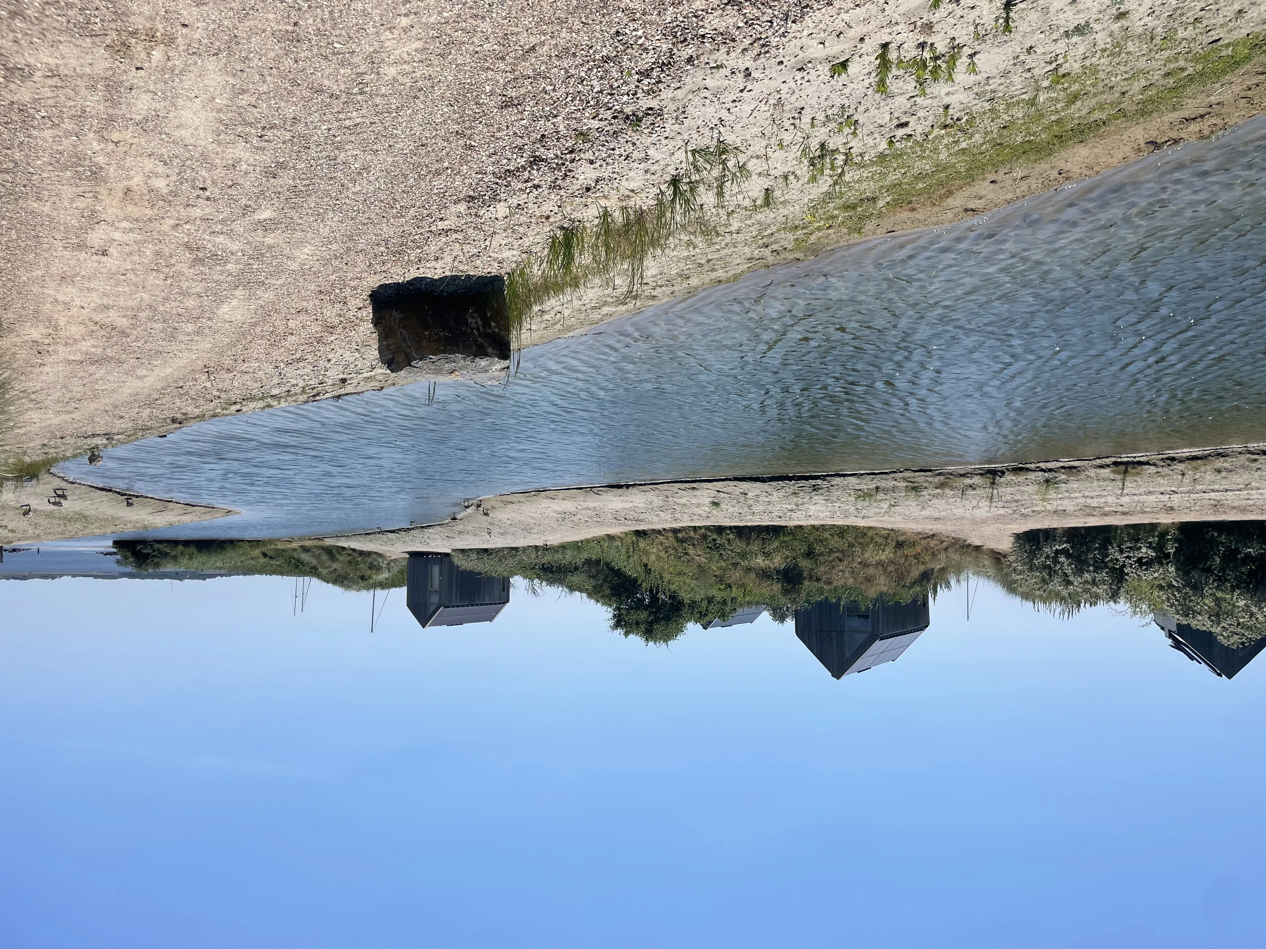 Lagune mit Steinbegrenzung und Ferienhäusern im Hintergrund