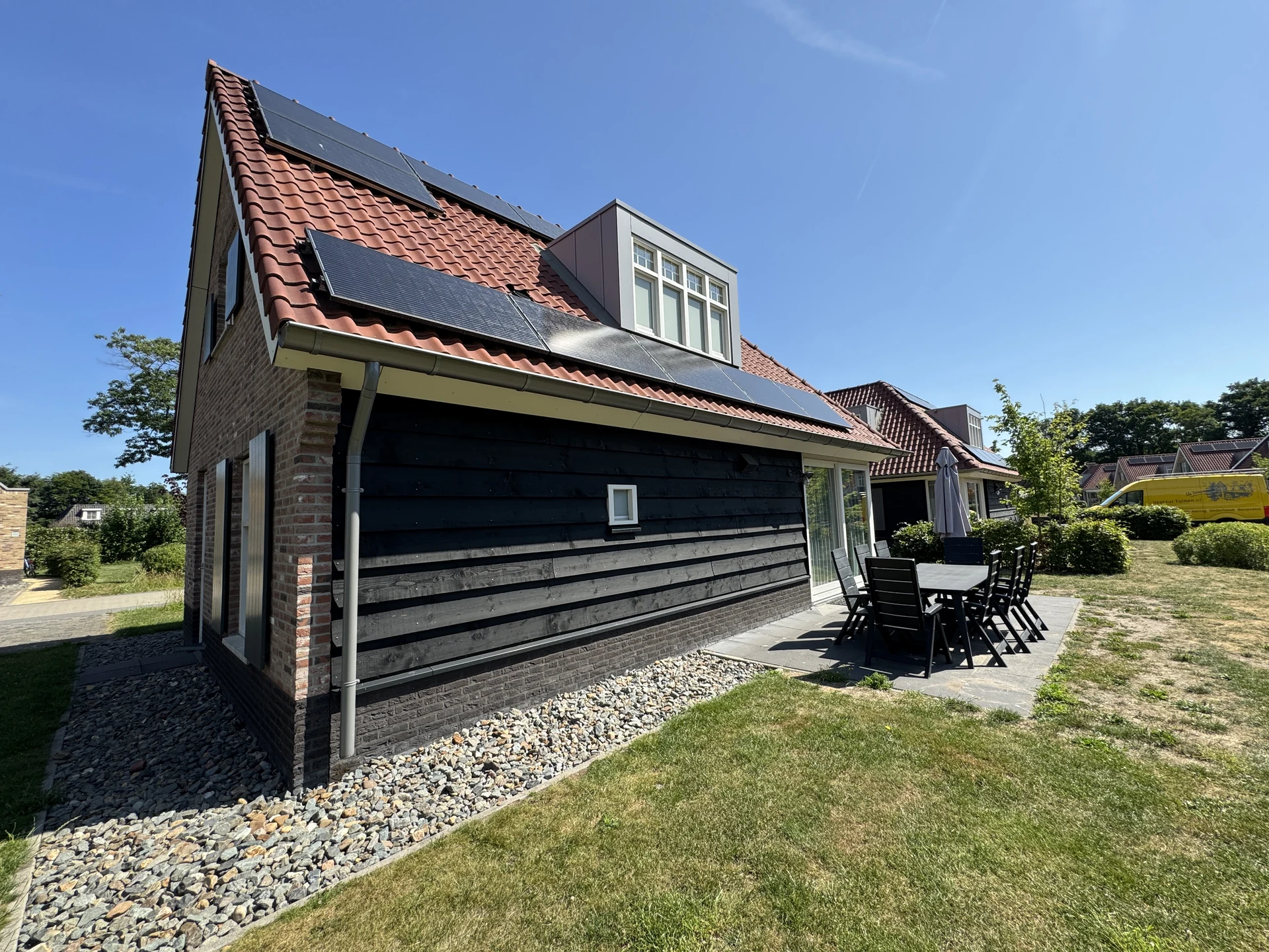Größeres Ferienhaus im Landal Kaatsheuvel mit Solarpaneelen auf dem Dach und großer gepflasterter Terrasse mit Esstisch für acht Personen