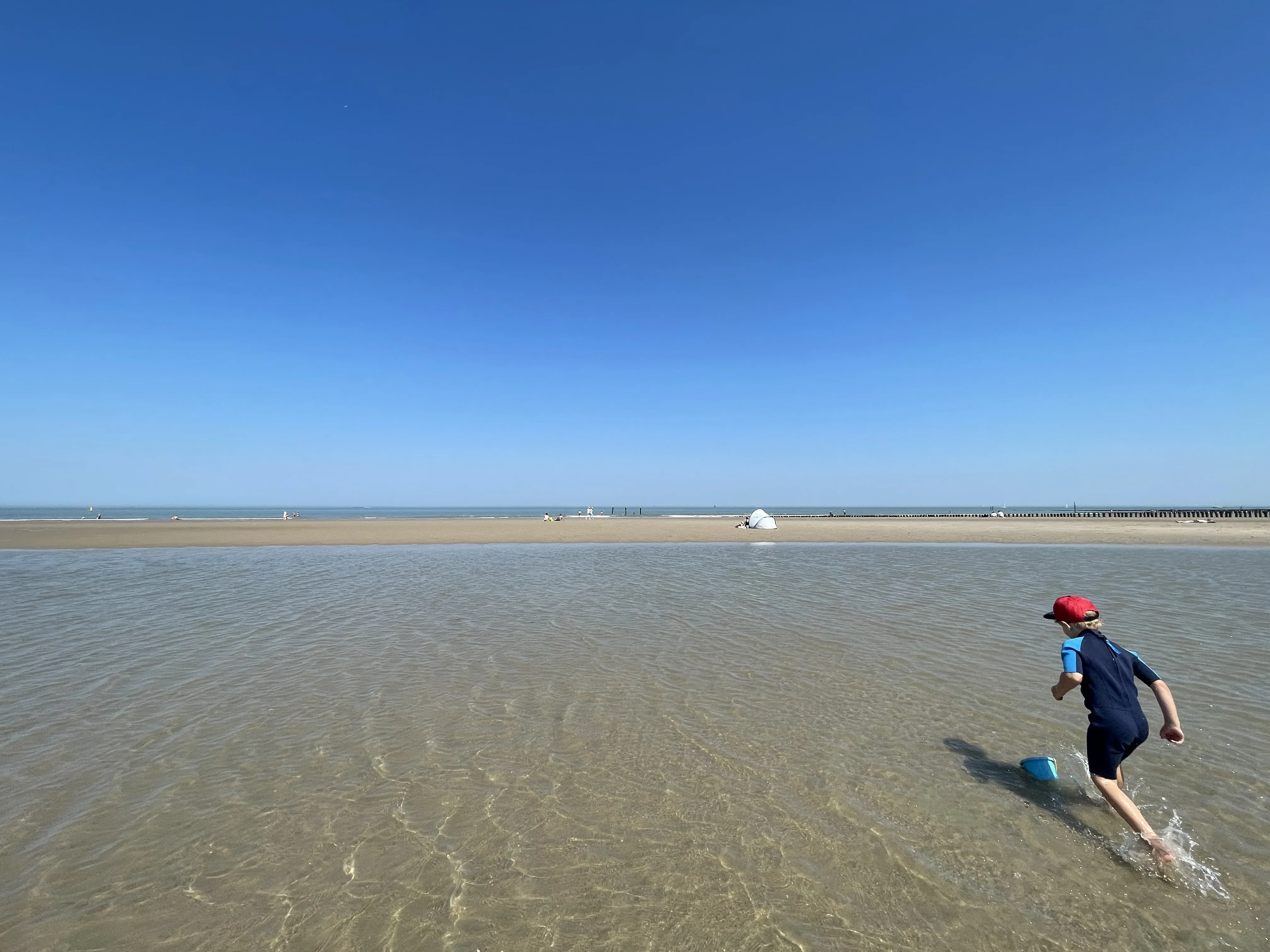 Kinder spielen im flachen Priel bei Ebbe am Strand von Cadzand-Bad