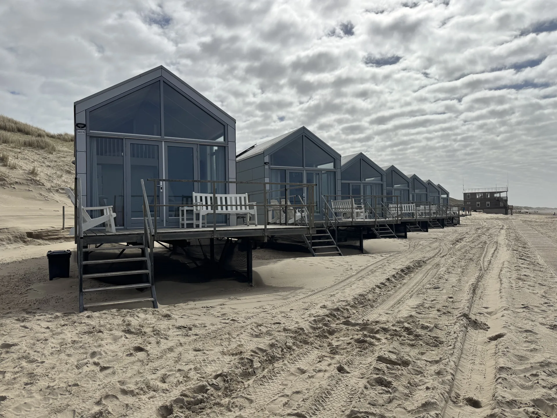 Strandhuisjes Julianadorp von der linken Seite gesehen - Reihe Holzhäuschen direkt im Sand