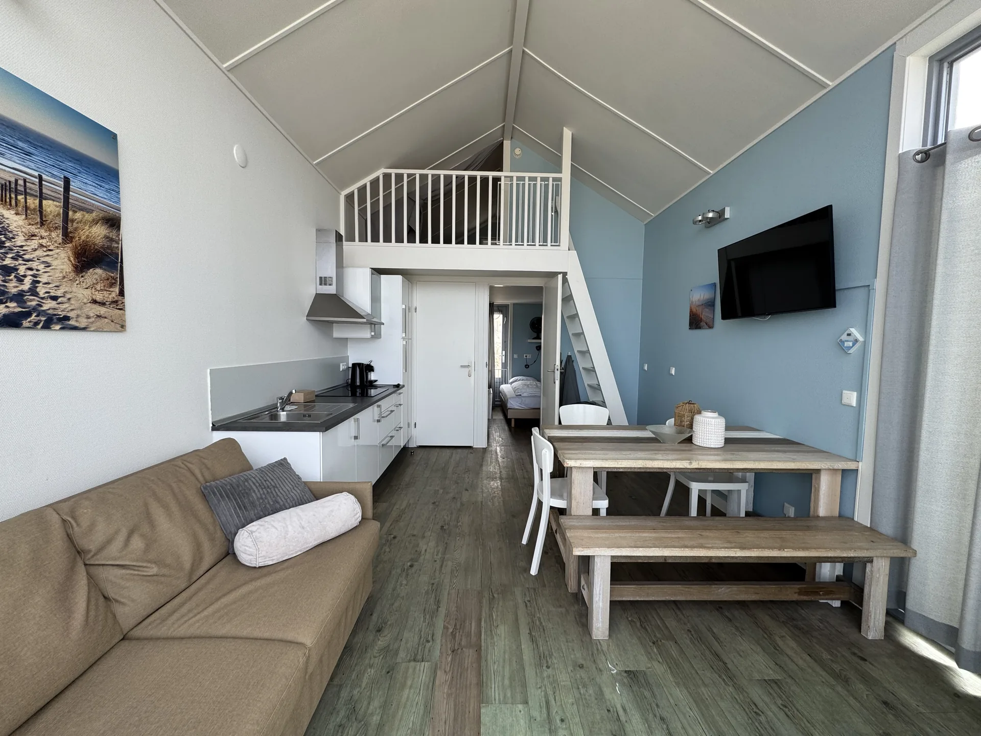 Wohnzimmer eines Strandhäuschens mit Sofa und großer Glasfront zum Meer