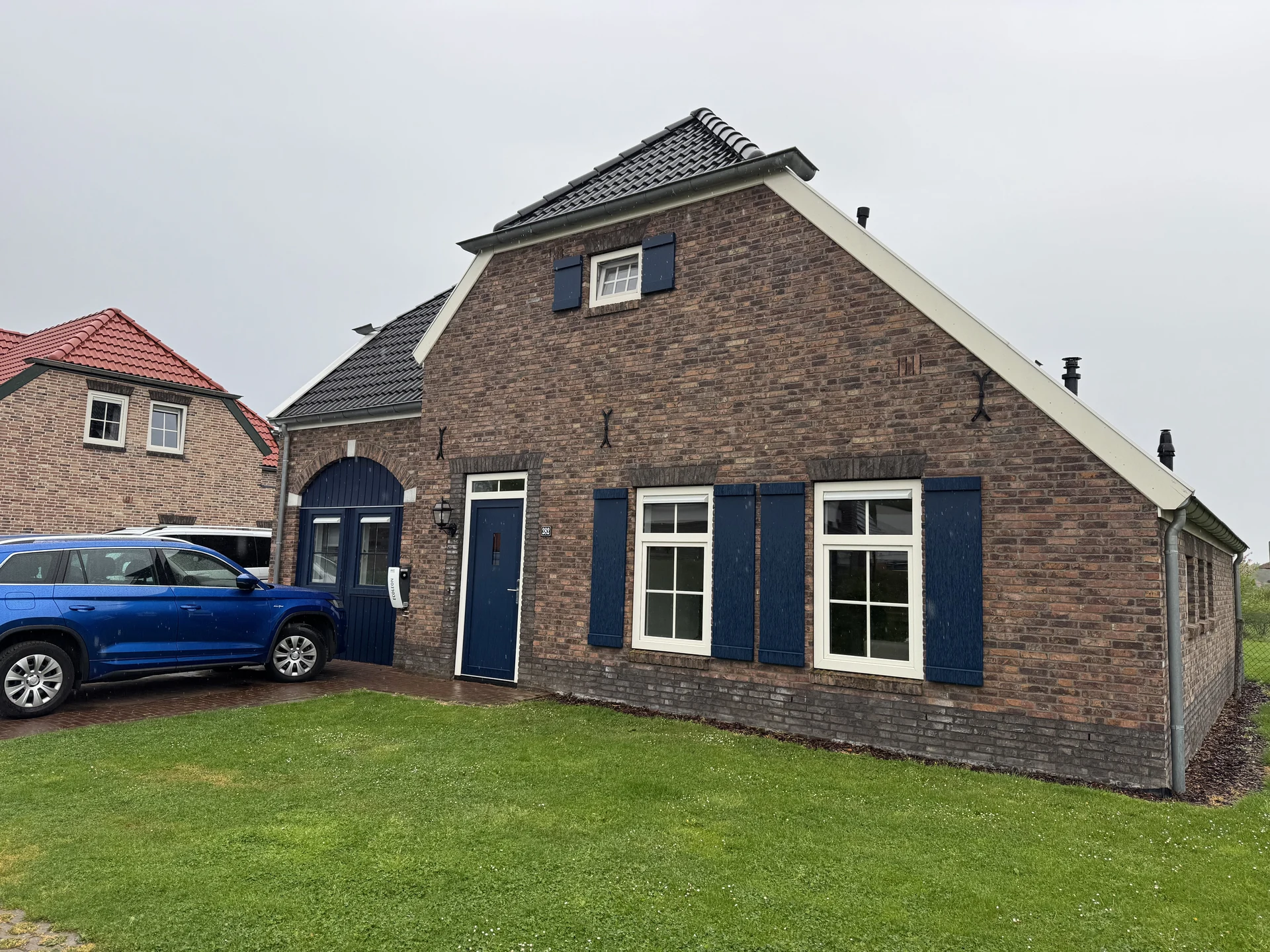 Bauernhaus mit blauen Fensterläden und Stellplatz für das Auto vor der Tür