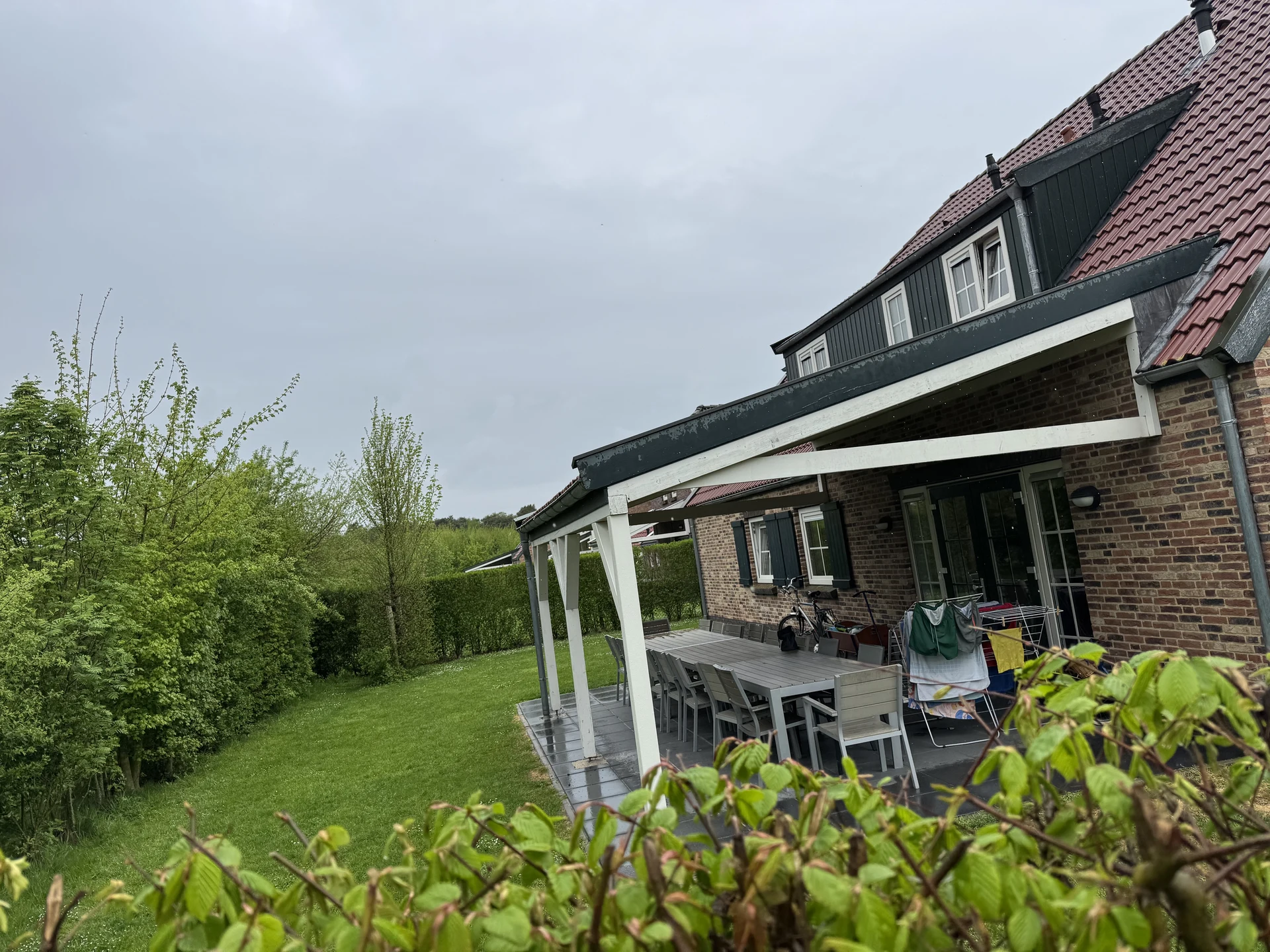 Überdachte Terrasse eines Bauernhauses mit langem Esstisch und Garten