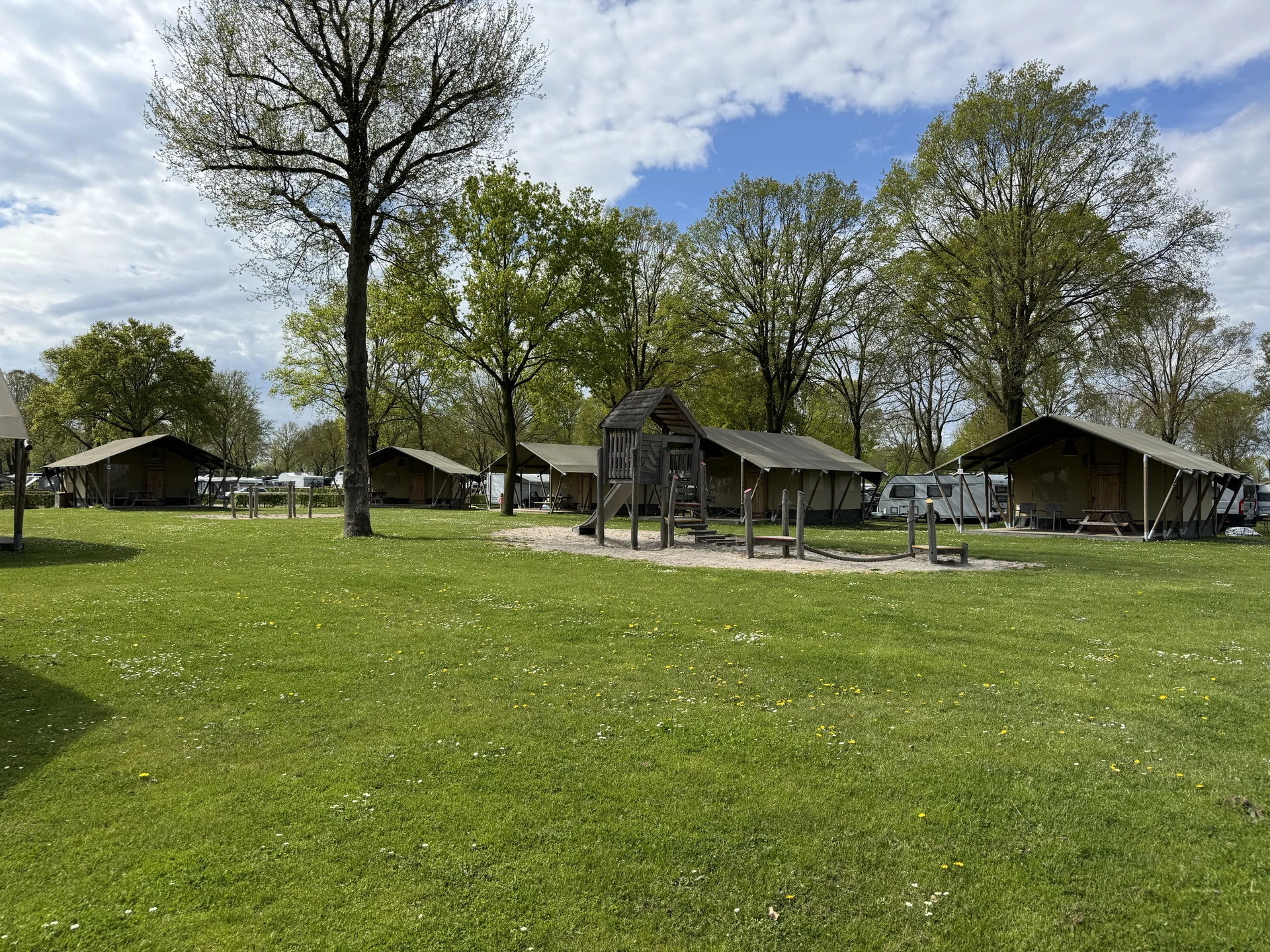 Safari-Zelte rund um einen Holzspielplatz auf der Wiese von De Leistert