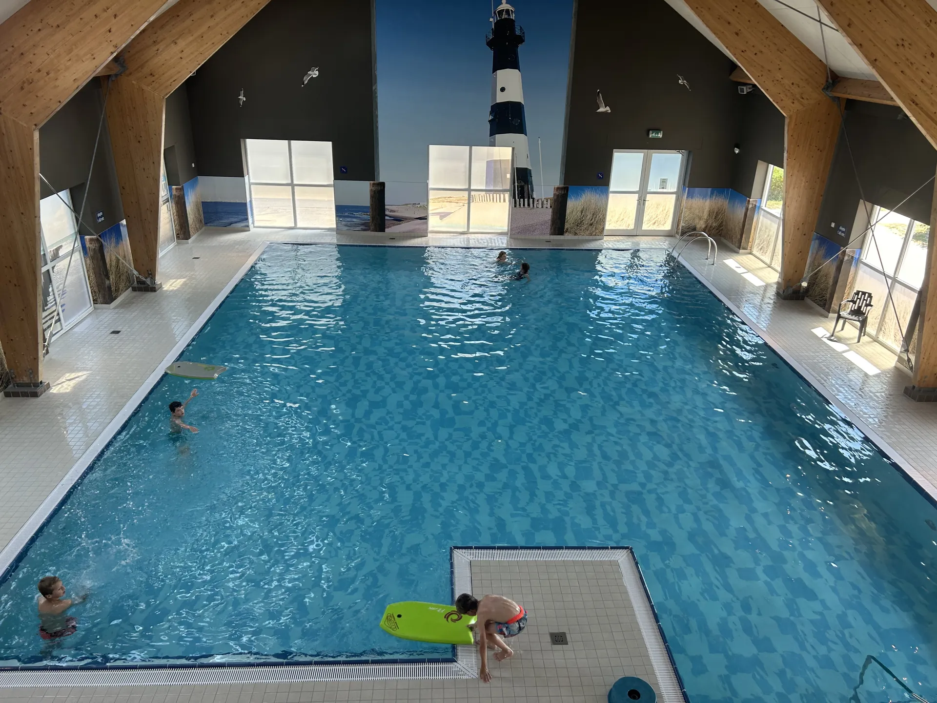 Hallenbad im Dormio Strand Resort Nieuwvliet-Bad mit Leuchtturm-Wandbild und großem Schwimmbecken ohne Rutschen