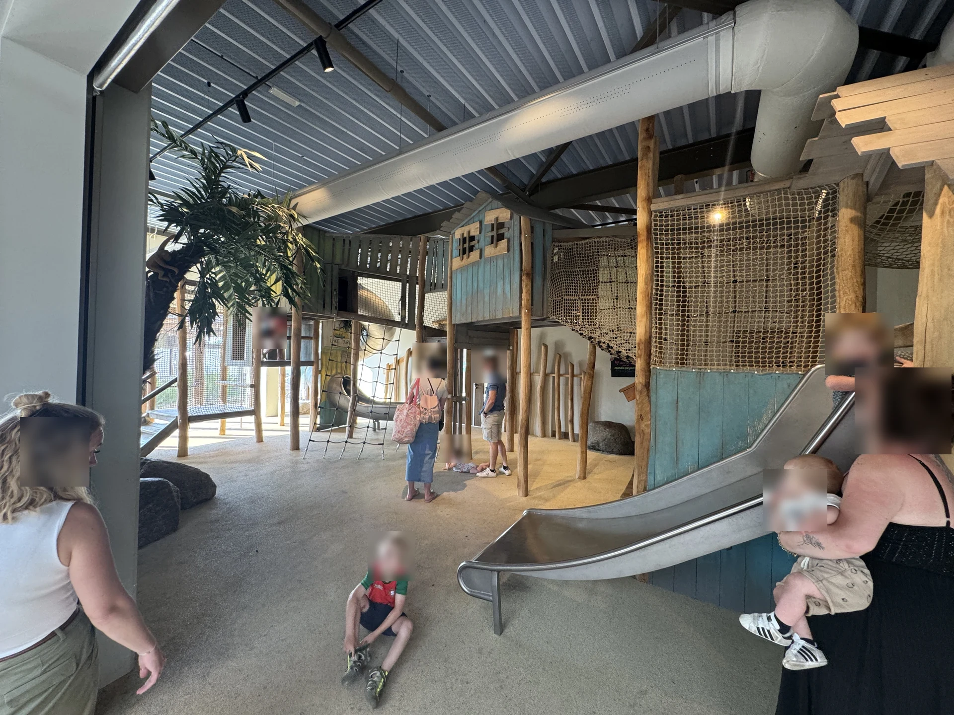 Indoor-Spielscheune im Lake Resort Beekse Bergen mit mehrstöckigen Holztürmen, Kletternetzen über zwei Ebenen, breiter Metallrutsche und Sandboden