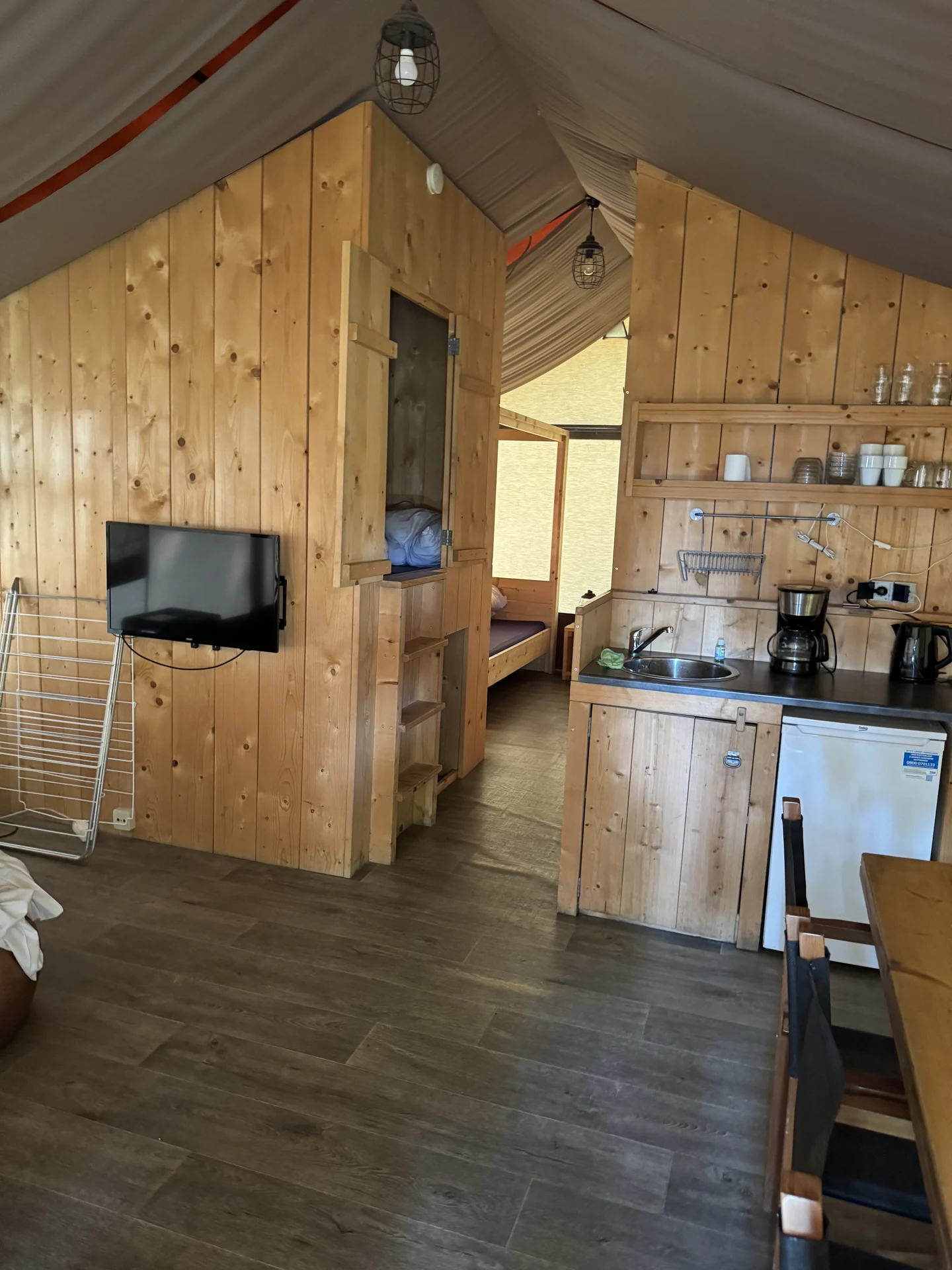 Blick in die Küchenzeile eines Safari-Zelts im Lake Resort Beekse Bergen mit offenen Regalen und Geschirr