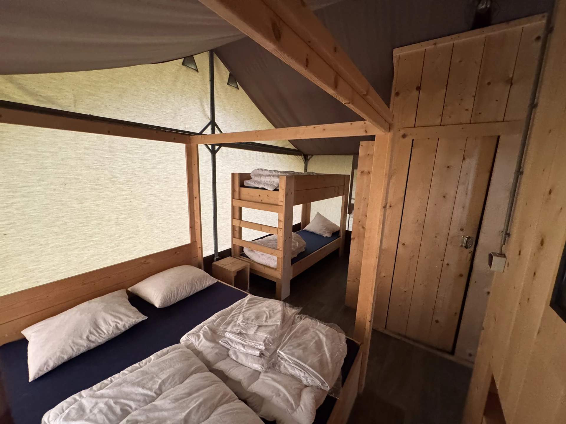 Schlafbereich in einem Safari-Zelt im Lake Resort Beekse Bergen mit Doppelbett und dahinter abgetrenntem Etagenbett für Kinder