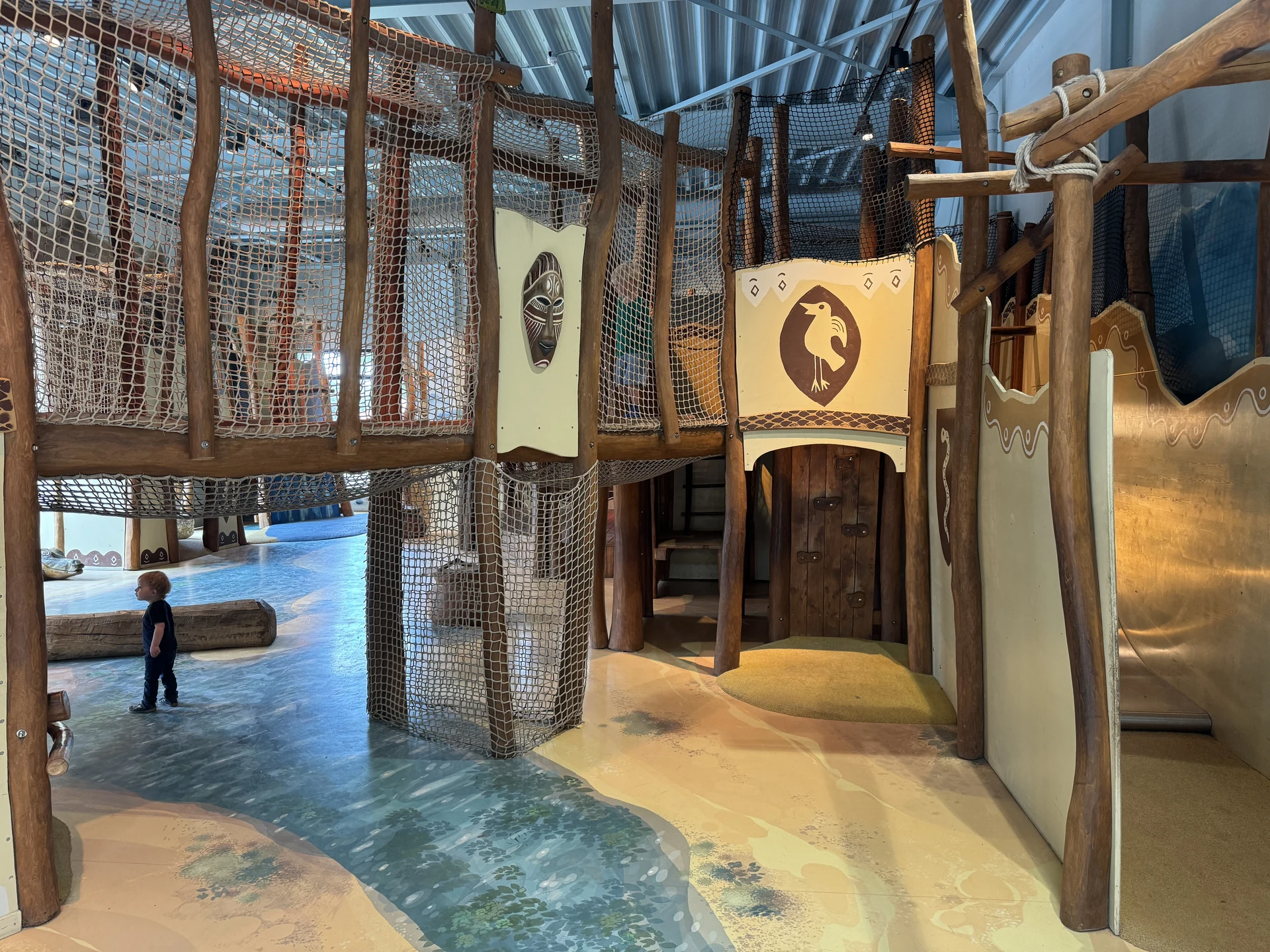 Indoor-Spielplatz in Karibu Town im Safari Resort Beekse Bergen mit afrikanischer Holz-Thematisierung, Kletternetzen und Wandpaneelen mit Tiermasken