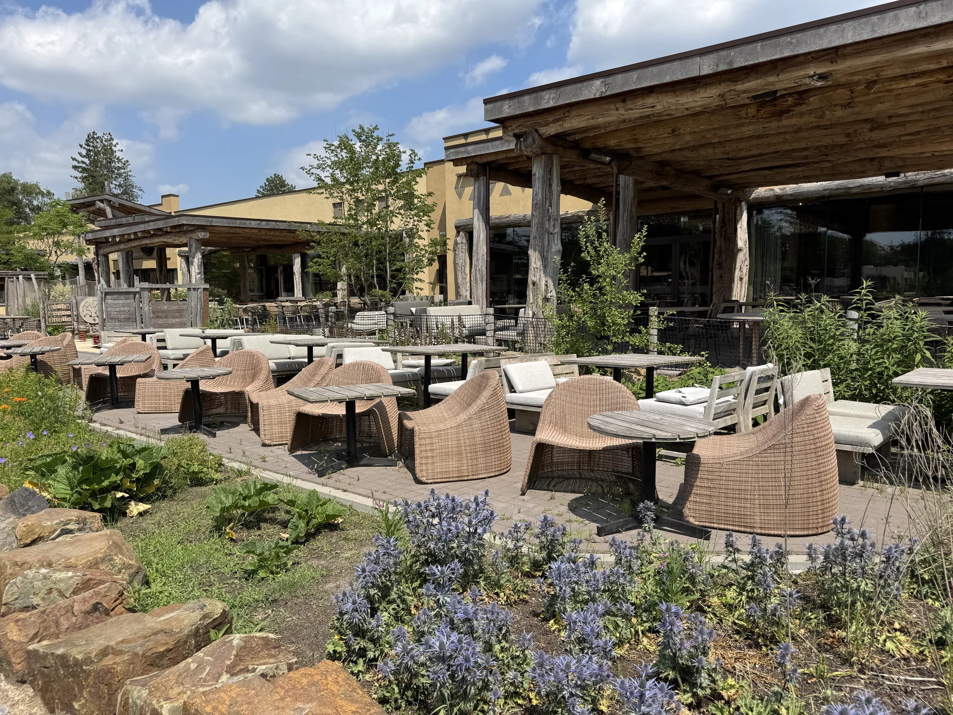 Terrasse des Restaurant Moto im Safari Resort Beekse Bergen mit Korbsesseln unter einem Dach aus verwitterten Holzstämmen