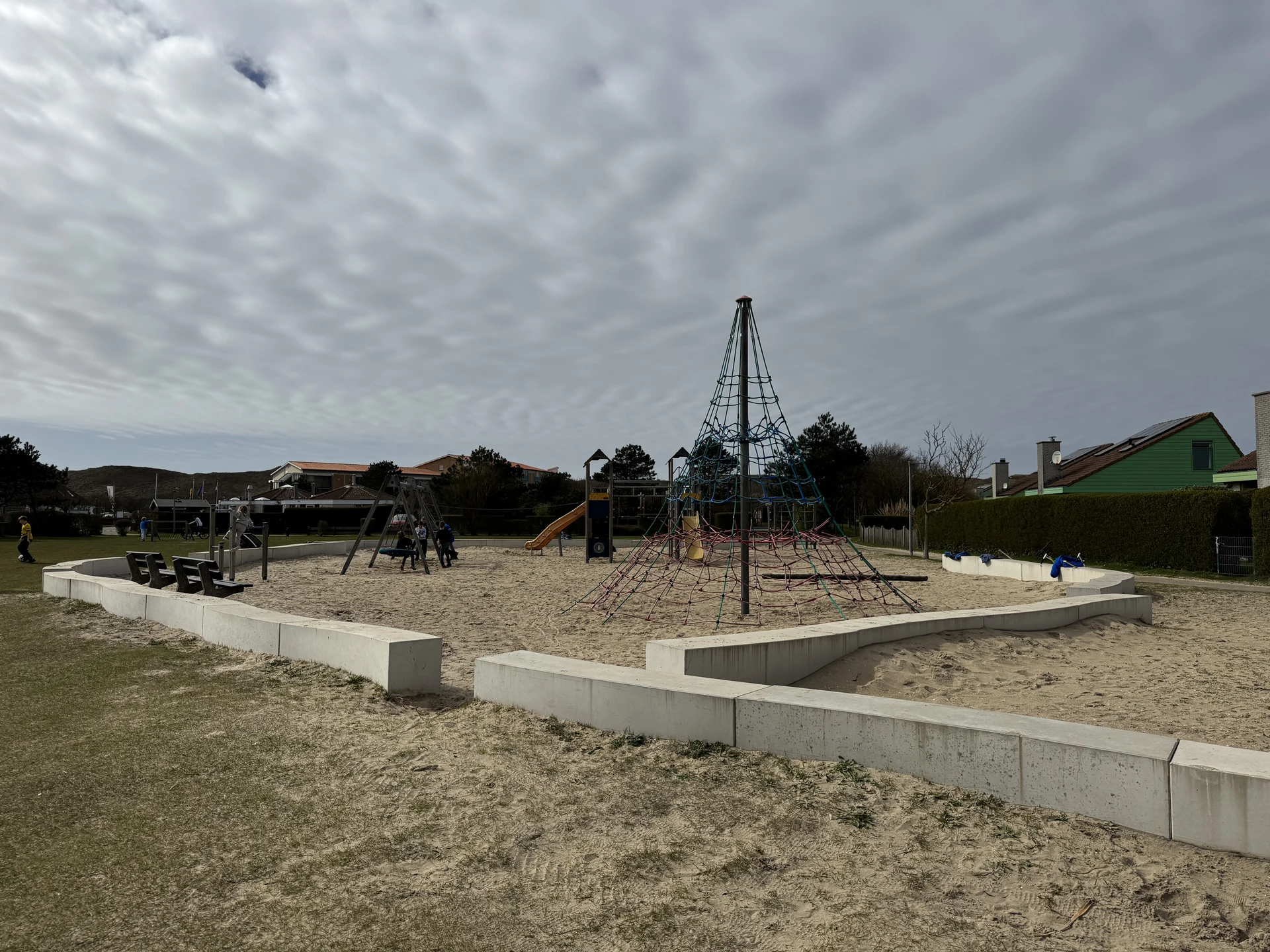 Sandspielplatz im Strandslag mit hoher Kletterpyramide und Betonsitzkanten
