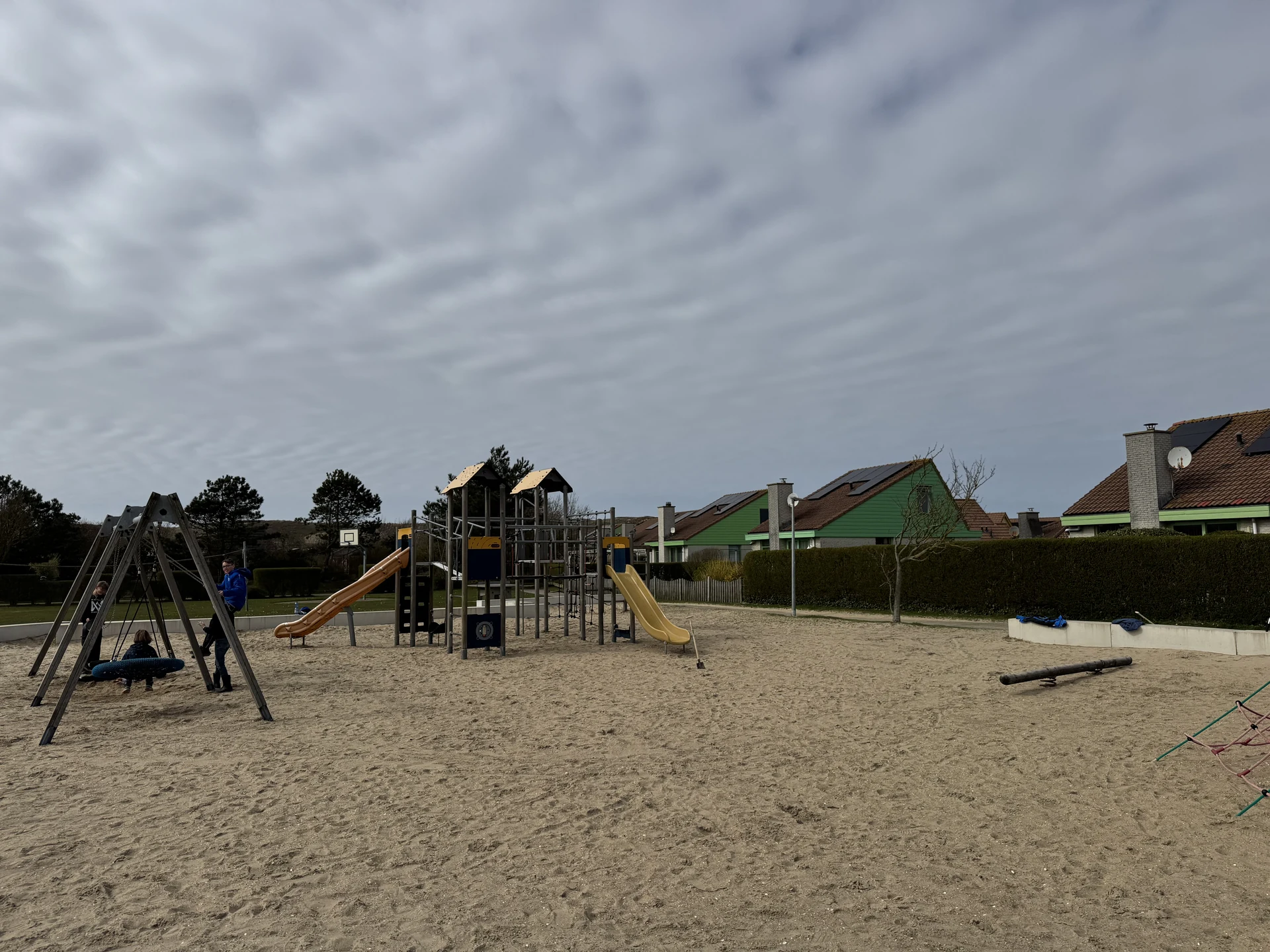 Nestschaukel, Klettergerüst und zwei Rutschen auf dem Spielplatz im Bungalowpark Strandslag
